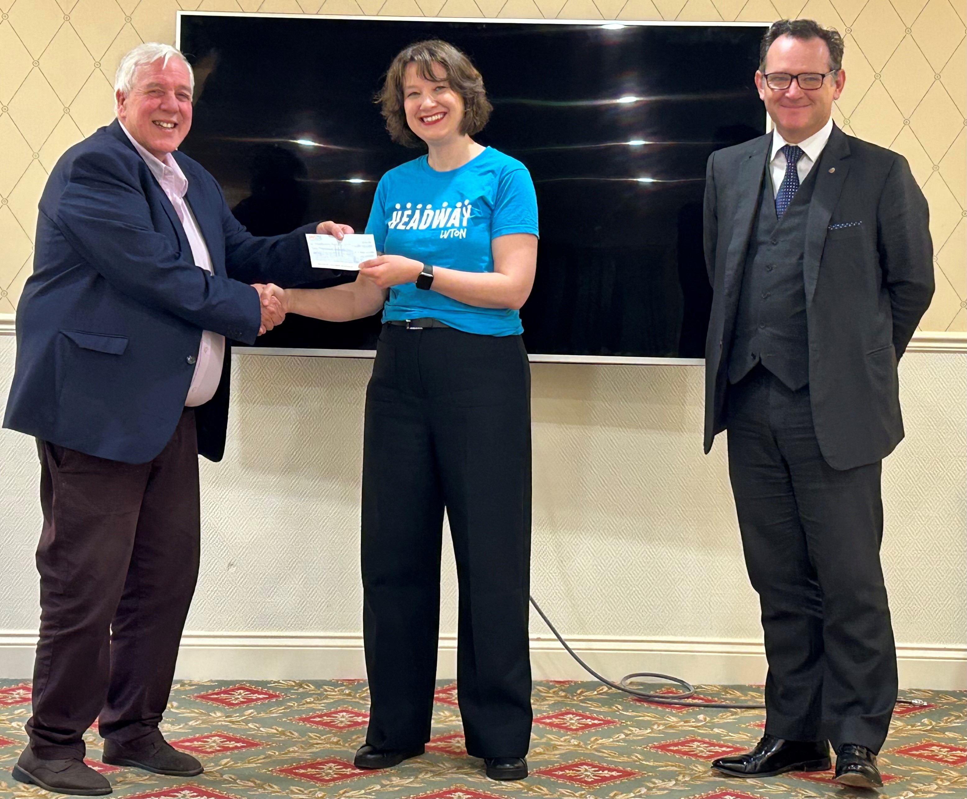 Staff member from Headway Luton is presented with a cheque for £1000 from Ron, owner of Collaborate network. They are standing in front of a very large TV in Luton Hoo.