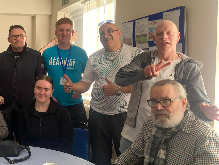 Freddie in a blue Headway Luton t-shirt with clients and staff smiling into the camera,