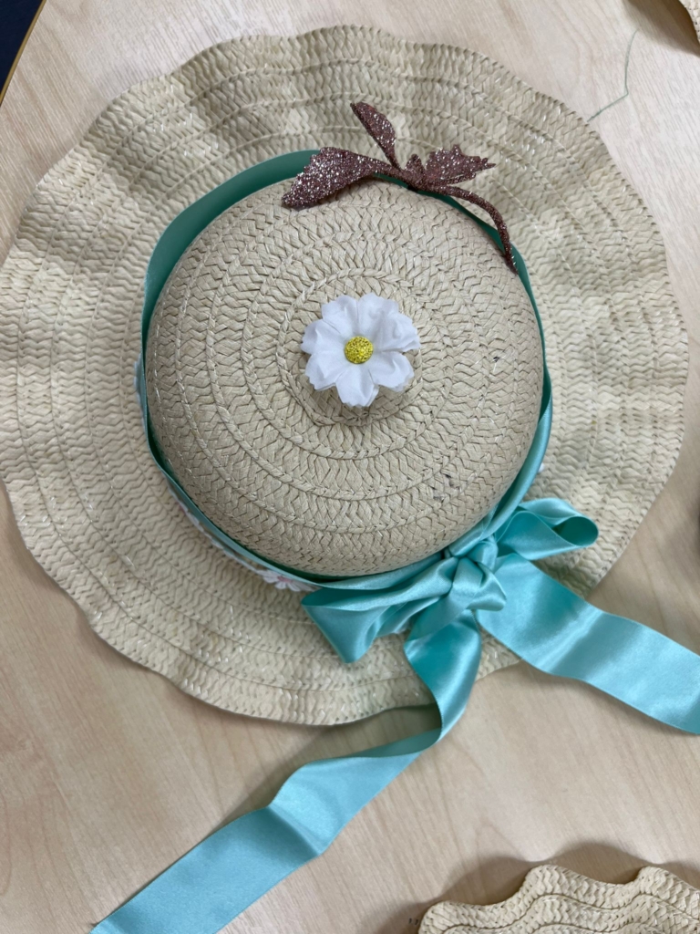 An Easter bonnet with a sky blue silk ribbon, white flower in the centre and a gold butterfly.
