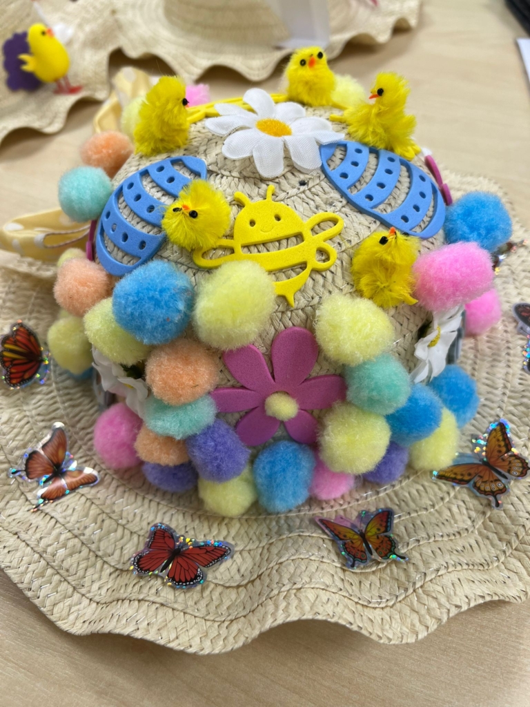 An easter bonnet decorated with butterflies on the brim and what seems like hundreds of mini-pompoms everywhere else!
